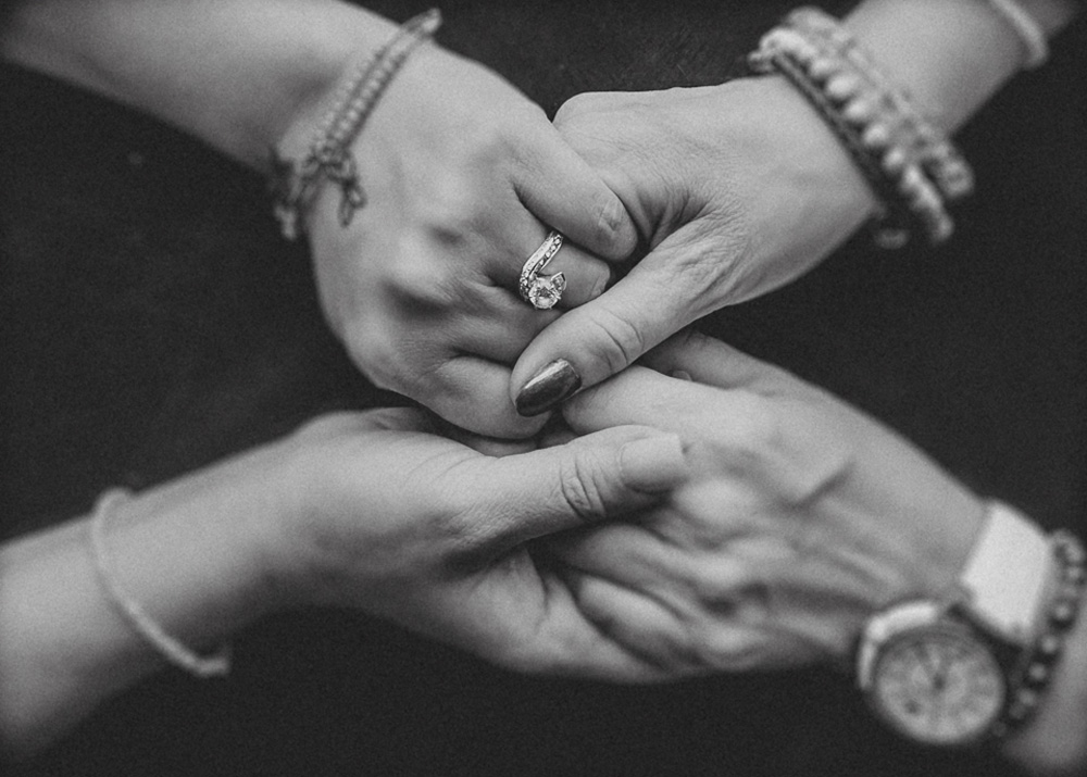 closeup hands holding, with focus on engagement ring, black and white