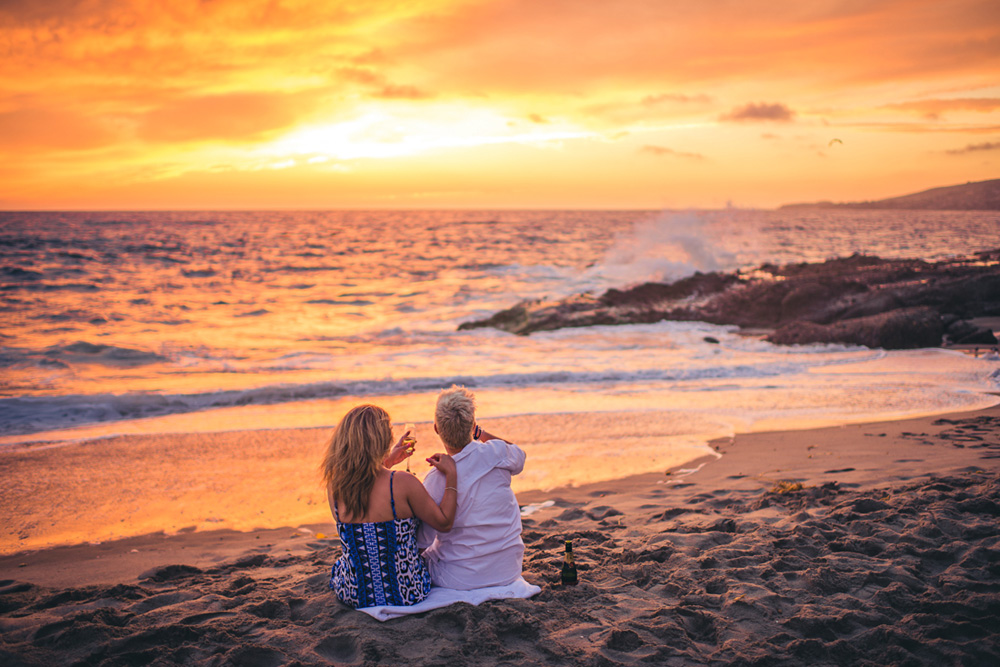 Montage laguna beach engagement session, couple sitting on the sand, watching the sunset